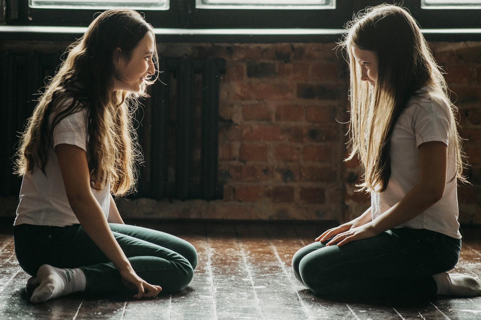 Two young girls sitting on the floor facing each other | Source: Pexels